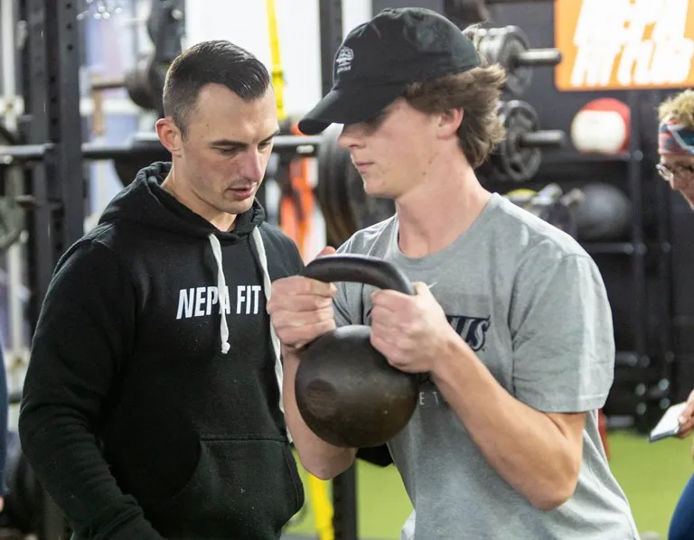 NEPA Fit Club coach cueing a high school athlete through a kettlebell lift