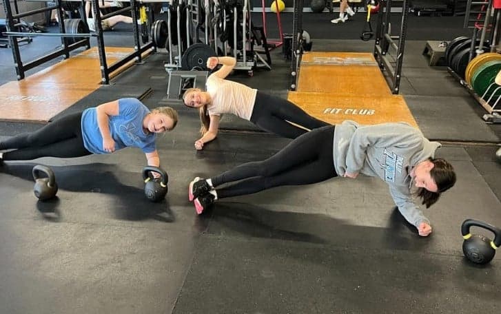 Three young athletes holding side planks with kettlebells at NEPA Fit Club